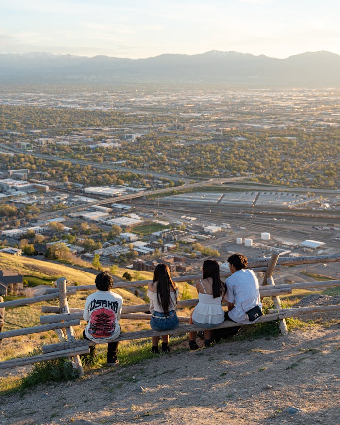 A group of young adults enjoy a scenic overlook of a city at sunset, capturing the essence of urban tranquility.